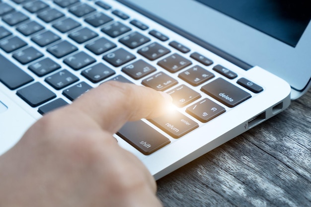 A close-up of a hand typing on a laptop keyboard with the cursor blinking in a search bar, implying the act of searching for unclaimed funds.