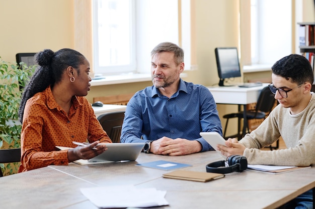 A student meeting with a financial aid advisor in a university office. The advisor is explaining the requirements for maintaining financial aid eligibility, emphasizing the importance of academic progress and accurate reporting.